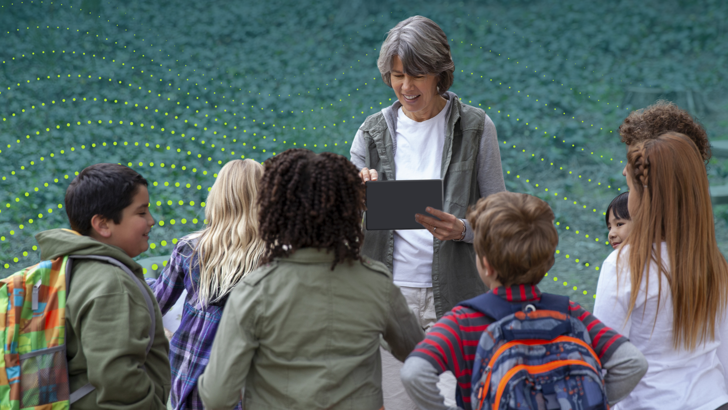 Teacher using wireless tablet with class outside