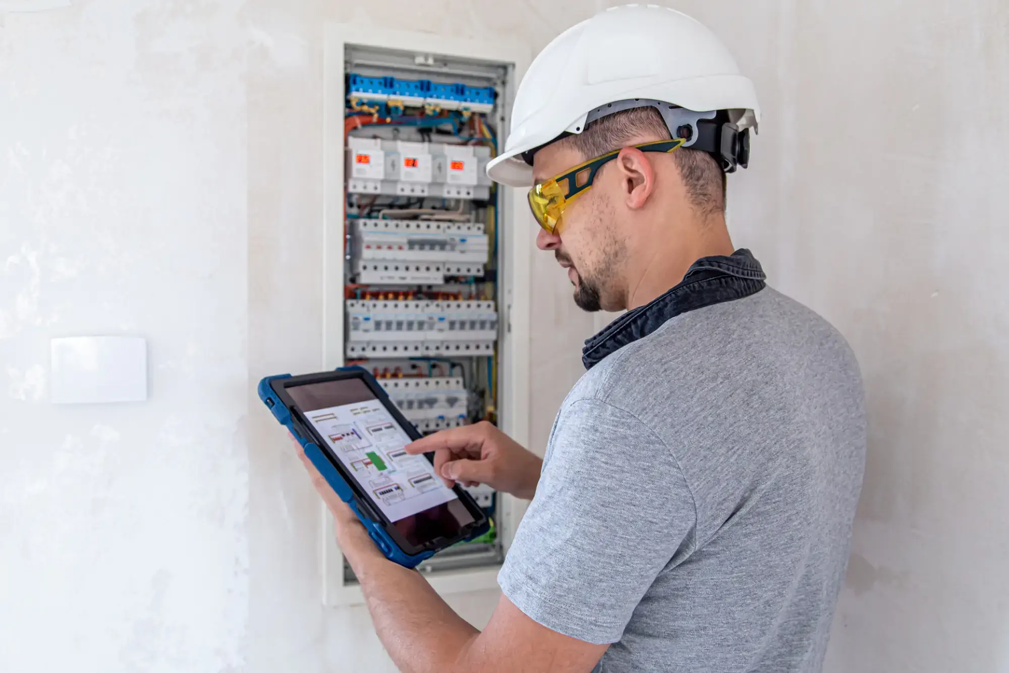 Electrical engineer using 5G wireless tablet for breaker panel inspection - photo