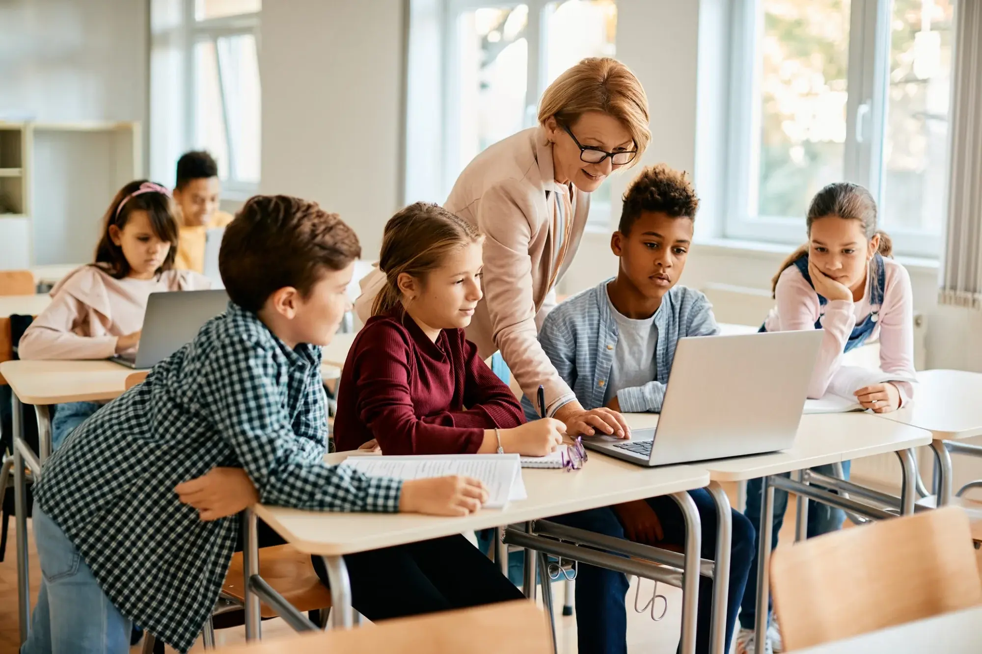 Teacher guiding students using 5G cellular laptop in classroom - photo